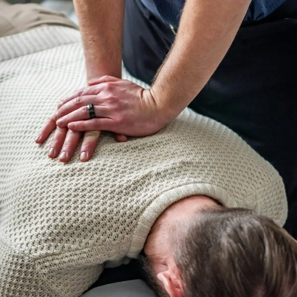 A practitioner gives a patient a hands-on adjustment to the upper back