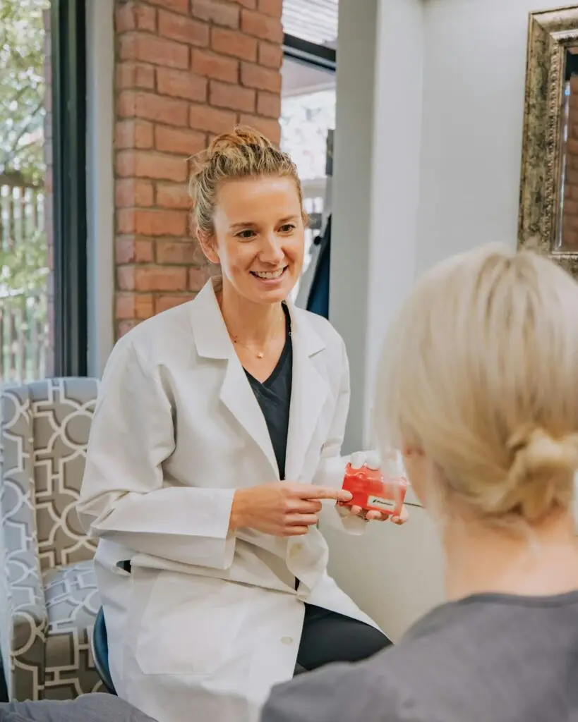 A smiling provider in a white coat talks with a patient in a bright, comfortable office